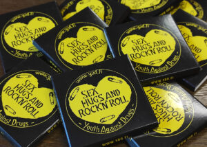 kondomipakkauksia, joissa keltainen sydän, jossa lukee sex, hugs and rock'n'roll